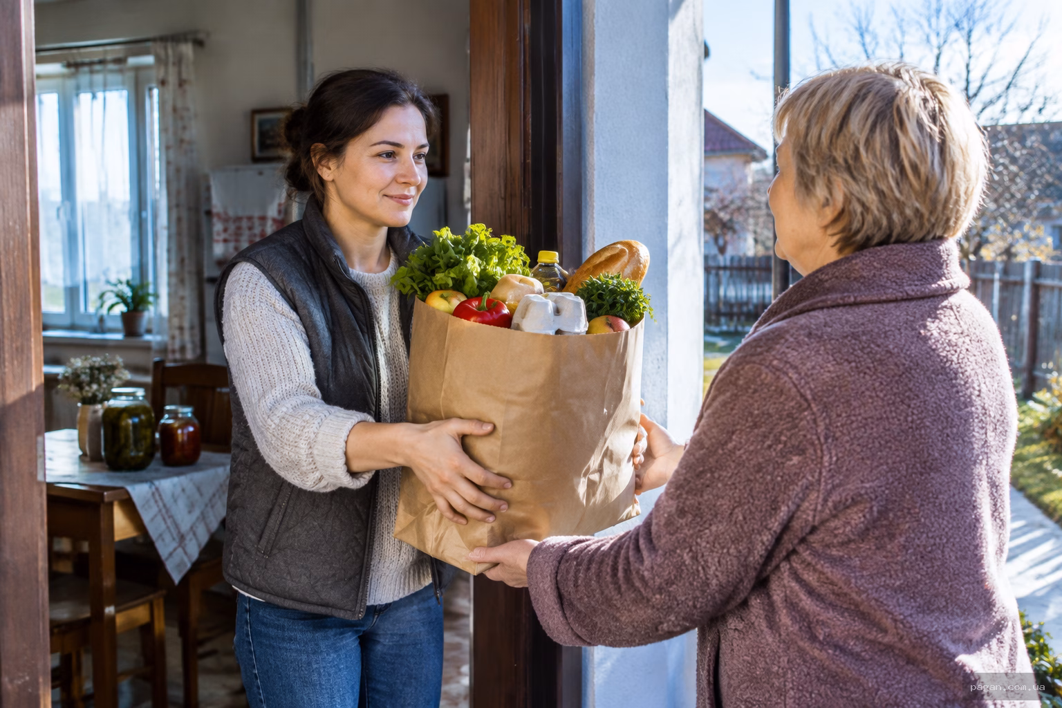 Жінка передає сусідці пакунок із продуктами через поріг дому