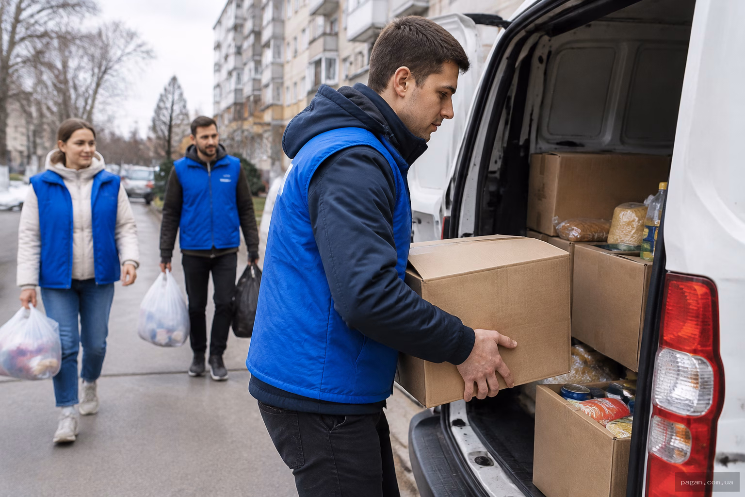 Волонтер завантажує коробки з продуктами у фургон на міській вулиці